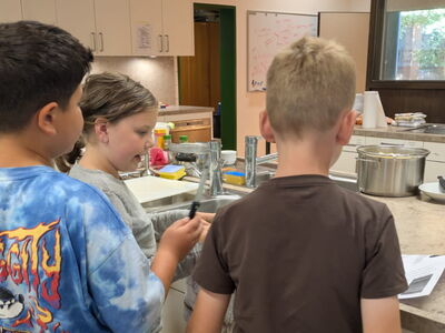 Kinder stehen in der Küche und beraten sich.